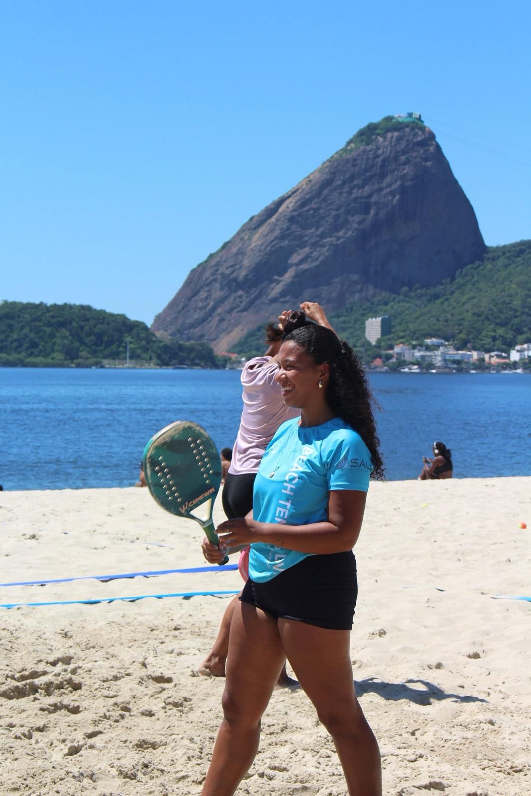 Aluna iniciante sorrindo com raquete na Praia do Flamengo