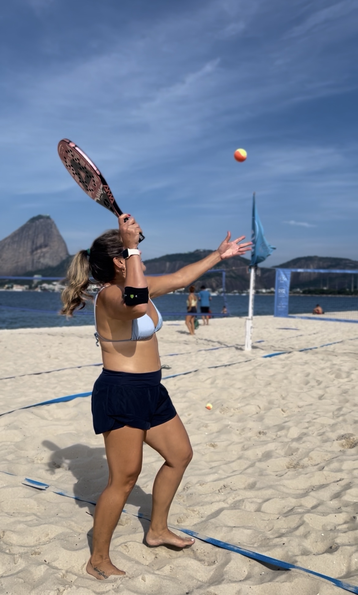 Jogadora sacando com o Pão de Açúcar ao fundo